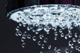 Close up image of running shower head with droplets of water being clearly seen.